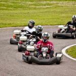 Enfants pilotant des karts rouges et blancs sur un circuit de loisir engazonné