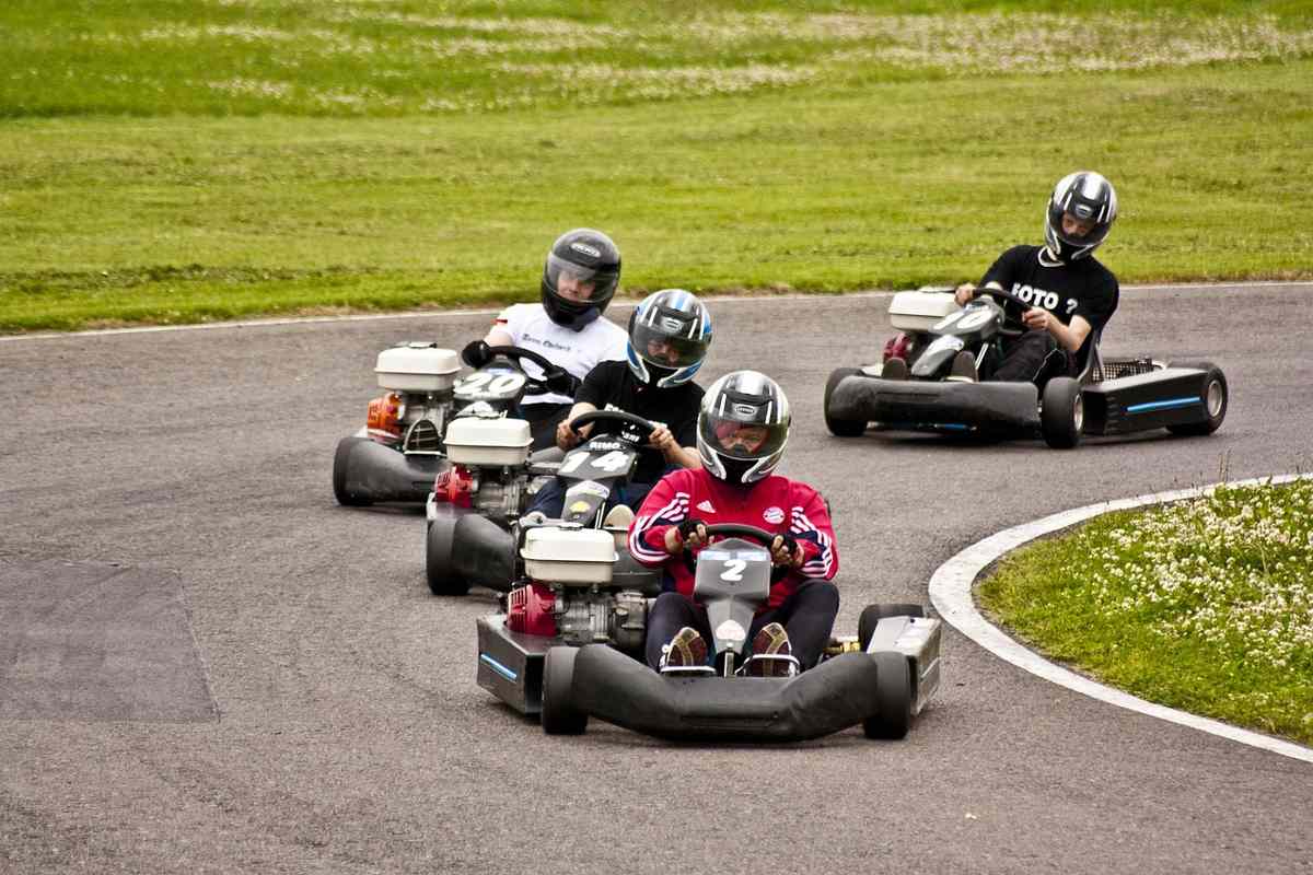 Enfants pilotant des karts rouges et blancs sur un circuit de loisir engazonné