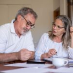 Homme et femme âgés en conversation, documents et tasse sur une table devant eux