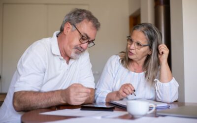 Homme et femme âgés en conversation, documents et tasse sur une table devant eux