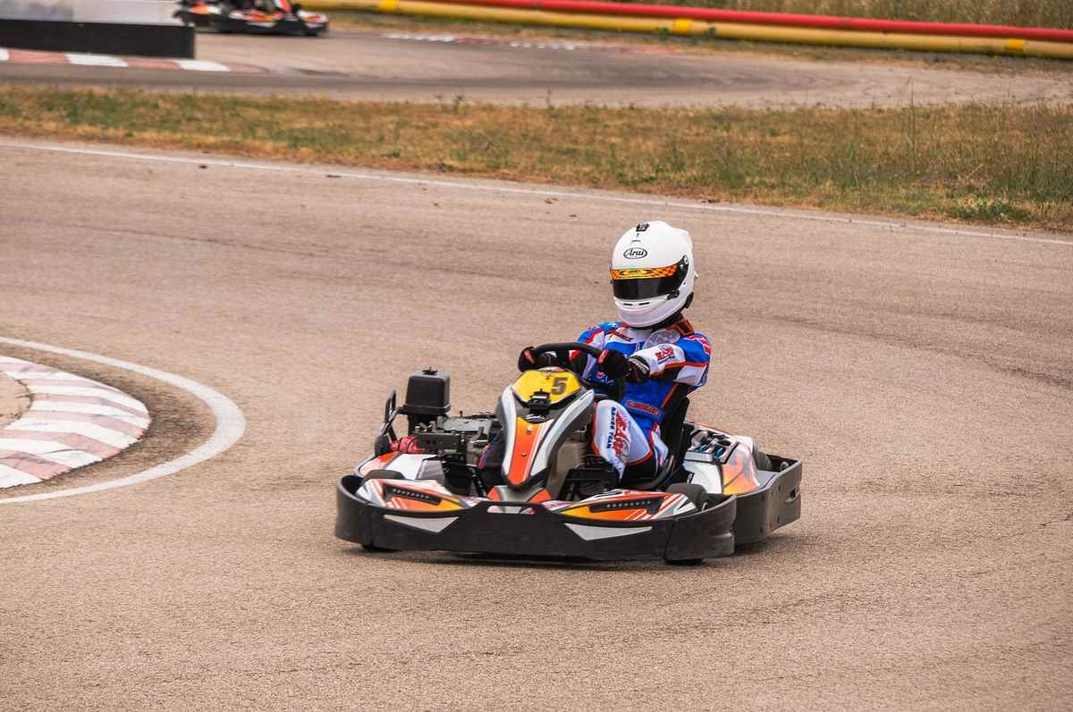 Un coureur en combinaison pilote un kart sur circuit Un coureur en combinaison pilote un kart sur circuit