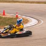 Un coureur en combinaison jaune pilote un kart sur piste courbe