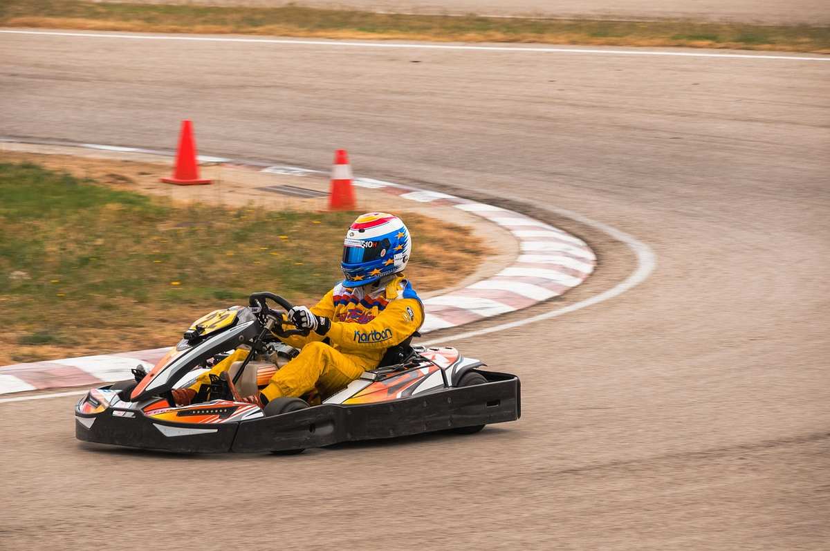 Un coureur en combinaison jaune pilote un kart sur piste courbe