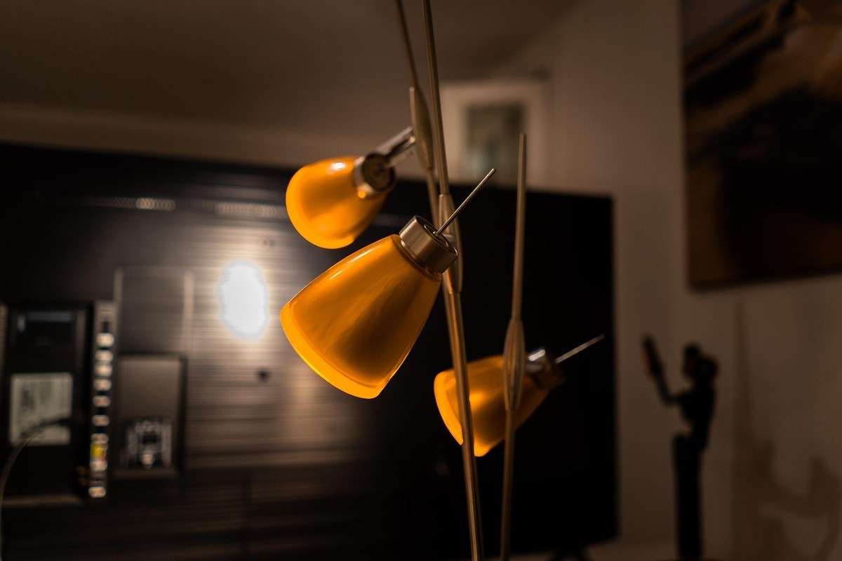 Lampadaire arc avec trois abat-jours jaunes illuminant un salon sans plafonnier Lampadaire arc avec trois abat-jours jaunes illuminant un salon sans plafonnier