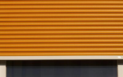 Volet roulant orange partiellement déroulé au-dessus d'une fenêtre sombre